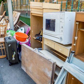 picture of junk including old microwave old dresser and plastic tupperware 