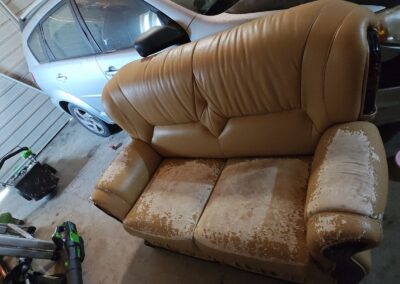 Old couch sitting in a cluttered Sacramento garage waiting for junk removal
