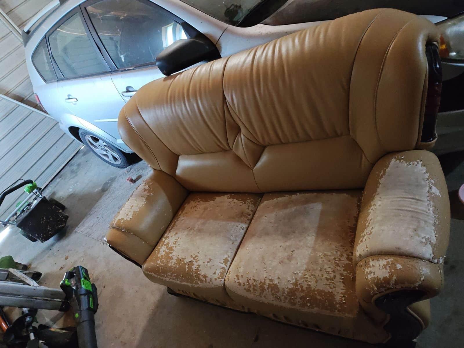 Old couch sitting in a cluttered Sacramento garage waiting for junk removal