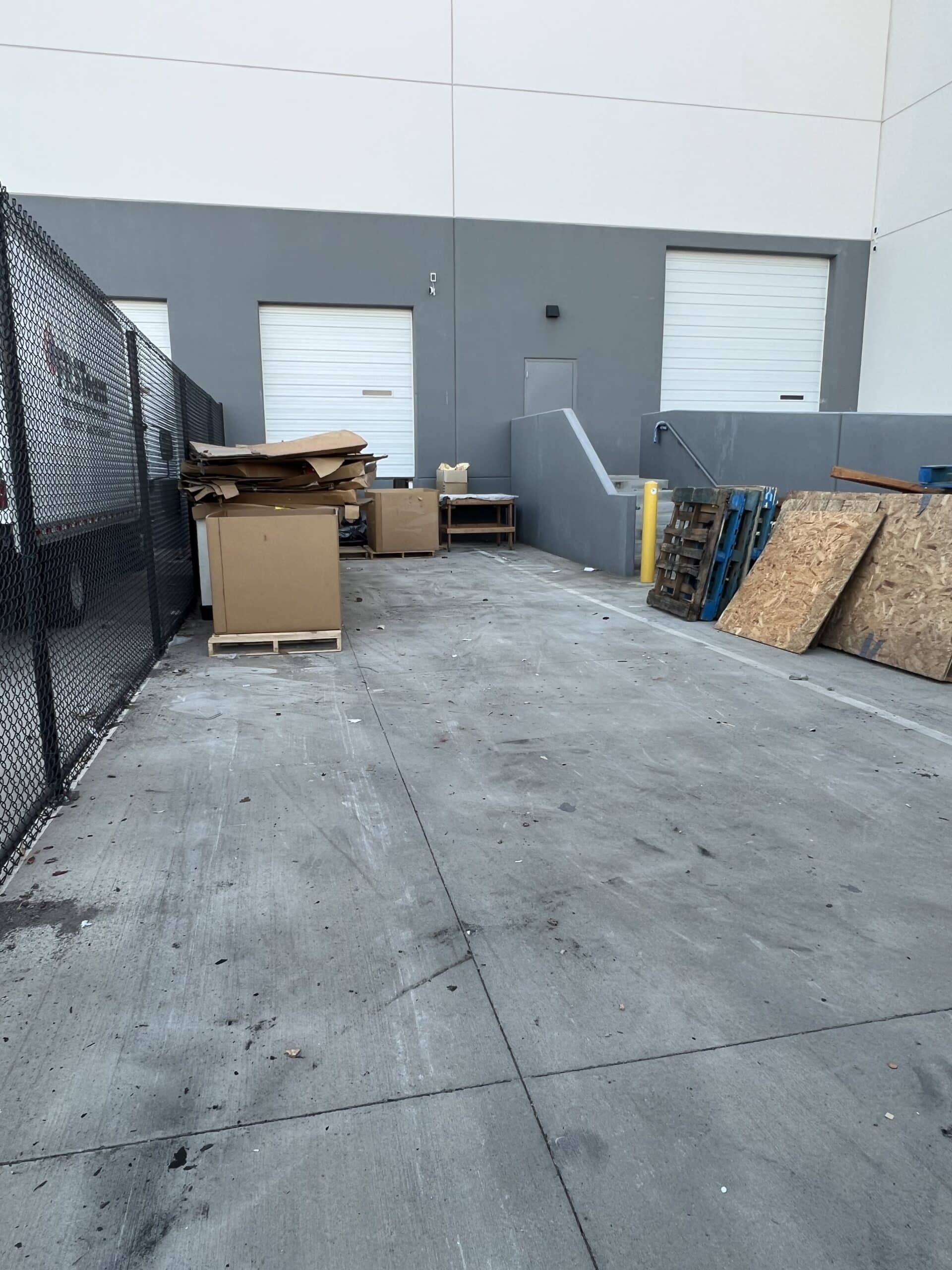 Piles of junk and debris stacked behind an industrial building in Sacramento awaiting removal