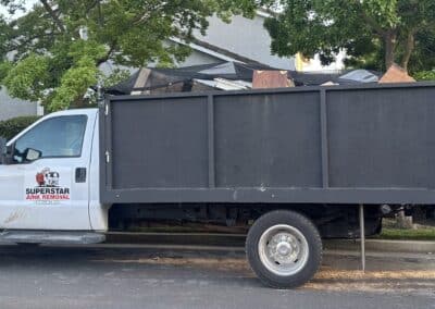 Full driver side view of Superstar Junk Removal truck parked in front of a Sacramento home